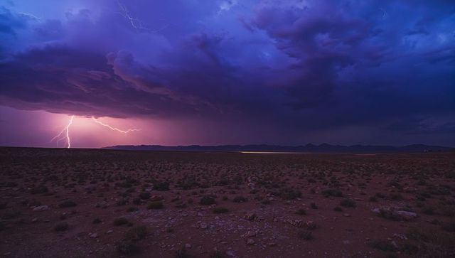 Lightning striking arid plain under dramatic thunderclouds at twilight
