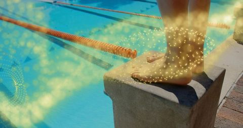 Swimmer poised on starting block with glowing sparkles by outdoor pool