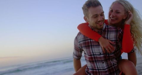 Joyful Couple Enjoying Piggyback Ride on Sunset Beach