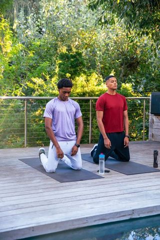Diverse men practicing mindfulness outdoor yoga by pool