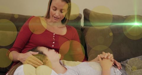 warm scene of a mother and daughter bonding on a sofa, with golden light and dots adding magical warmth. represents harmonious family relationships and open communication. ideal for promoting family themes, parenting blogs, or emotional connection content in media projects.