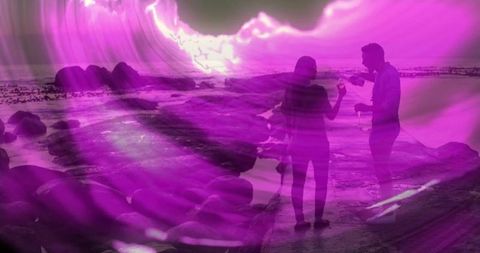 Romantic couple toasting on rocky beach in violet light
