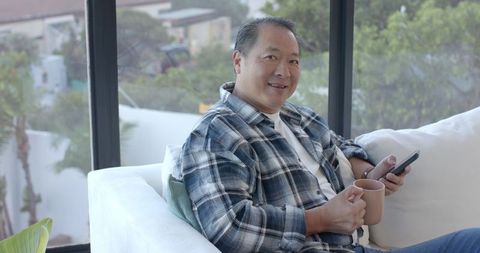 Asian {DES}, Relaxing with a Coffee on Comfy White Sofa in Modern Living Room
