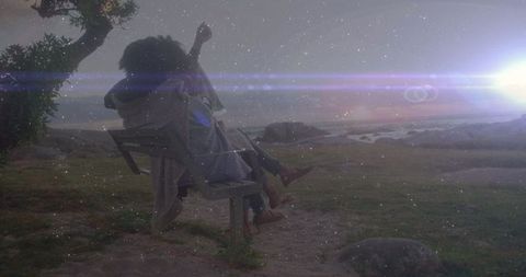 Couple embracing on coastal park bench under starry sky