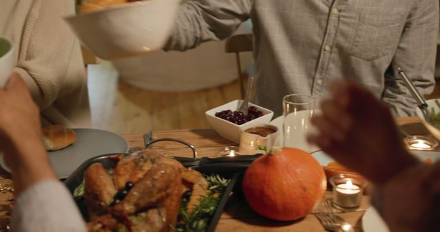 Group of people enjoying Thanksgiving dinner with traditional turkey and sides. Perfect for themes related to family gatherings, holiday celebrations, festive meals, and Thanksgiving traditions. Candlelight adds a warm, cozy atmosphere, making it suitable for advertisements or articles focused on holiday décor and heartwarming moments.