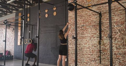 People exercising with medicine ball and pull-up bars in gym