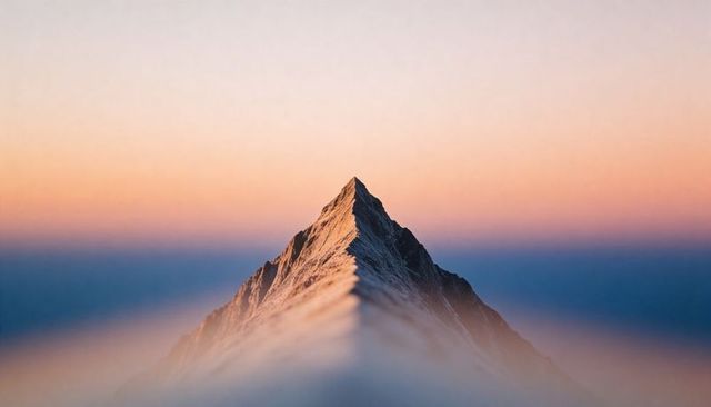 Solitary alpine peak piercing dawn alpenglow over foggy ridge, snow-capped summit
