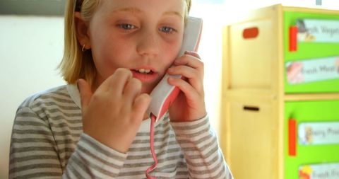 Young Girl Talking on Toy Phone in Classroom Setting