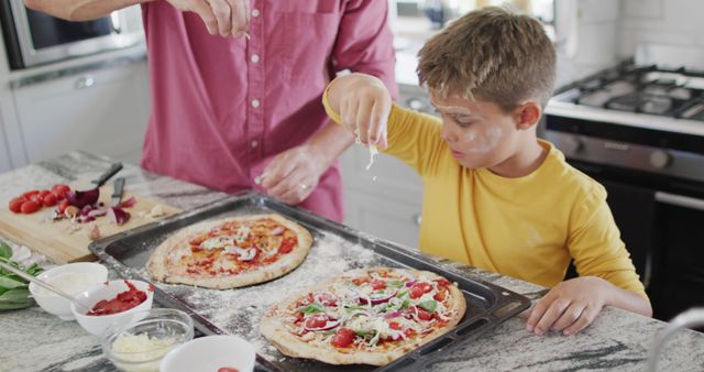 Father and son preparing homemade pizza using fresh ingredients in kitchen. Son sprinkling cheese while father helping. Captures family bonding, food preparation, and a fun activity. Perfect for blogs on family recipes, cooking tutorials, and advertisements for kitchen appliances.