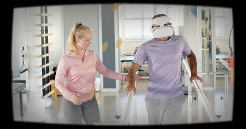 Virtual reality gait therapy patient walking between parallel bars while therapist guiding