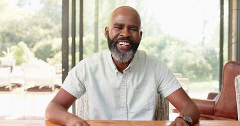 Smiling Man Sitting at Table Enjoying Video Call with Friends