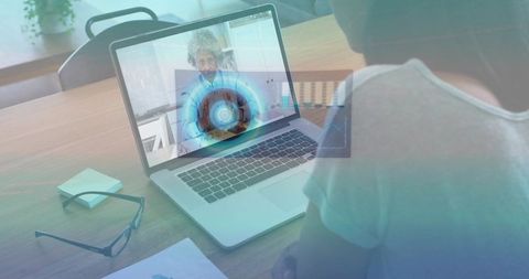 Woman working remotely watching video call with holographic data overlay on laptop