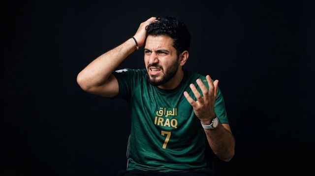 Frustrated iraqi football fan clutching head wearing green jersey number 7