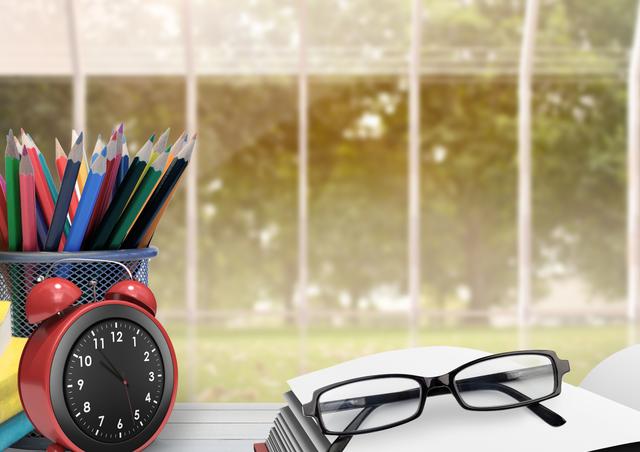 Digital composite image of pencil holder, alarm clock spectacles and book kept on table