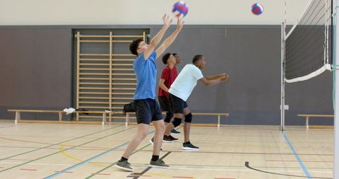 Multiethnic male volleyball players practicing blocking, passing and team drill in gym