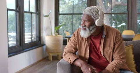Mature Man Relaxing with Headphones by Bright Window