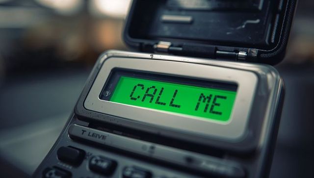 Retro flip phone displaying call me on green backlit lcd closeup for communication concept