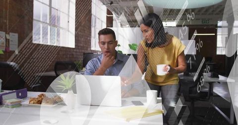 Colleagues collaborating over laptop in bright open office with data graphics overlay