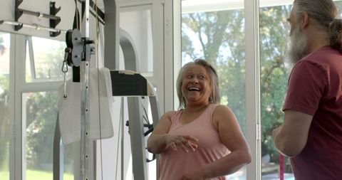 Senior Couple Exercising Together in Home Gym Supporting Each Other