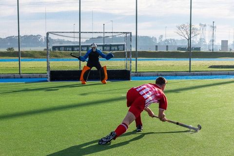 Intense Field Hockey Shot by Teenage Player Challenging Goalie Outdoors