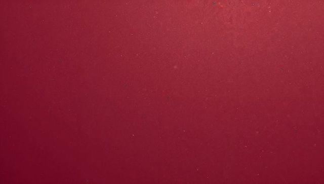 Maroon textured surface showing subtle dust flecks and fine scratches