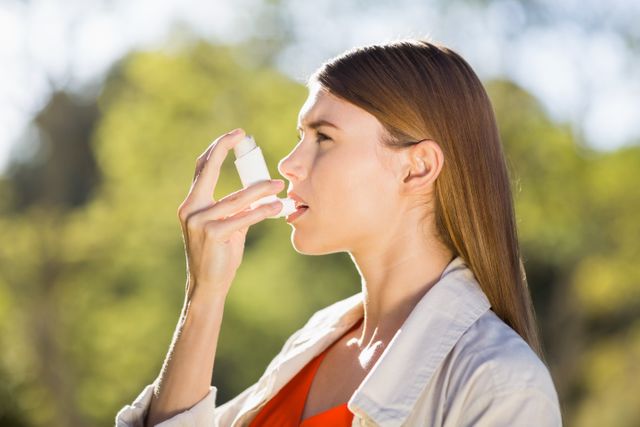 Woman using asthma inhaler in a park