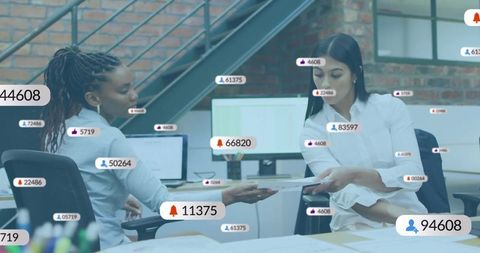 Female coworkers exchanging documents at modern office desk with analytics overlays