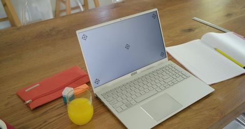 Minimal home office workspace with laptop showing calibration targets, notebook and juice