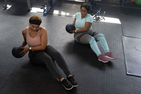 African american women doing medicine ball russian twists for core strength training