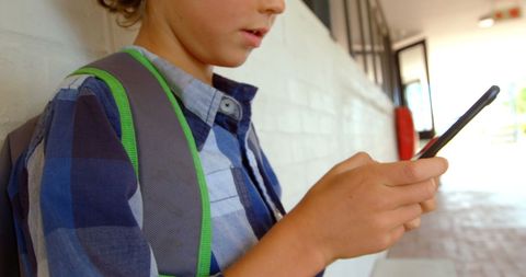 Schoolboy in Checkered Shirt Texting on Smartphone in School Corridor
