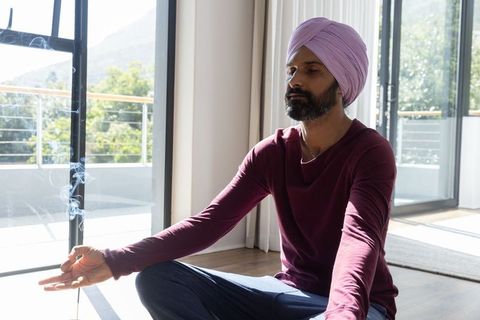 Indian Man Meditating in Sunlit Room with Incense Smoke