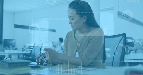 Businesswoman analyzing data in modern office with technology interface