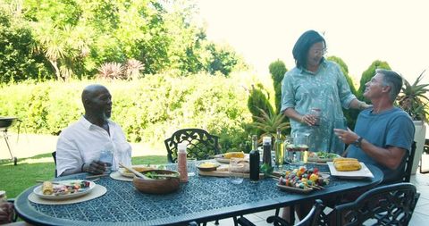 Diverse friends enjoying outdoor meal on sunny patio