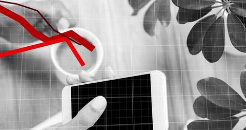 Overhead tapping smartphone with red downward trendlines on desaturated desk flatlay