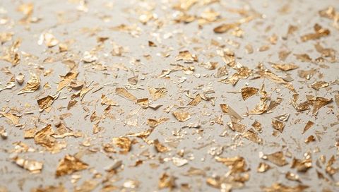 Scattered Gold Leaf Flakes on Cream Surface with Warm Metallic Sheen and Shimmer