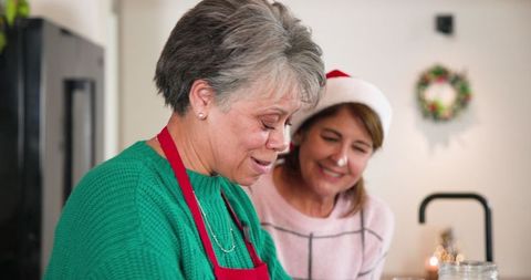 Senior mother and daughter sharing holiday joy in cozy kitchen