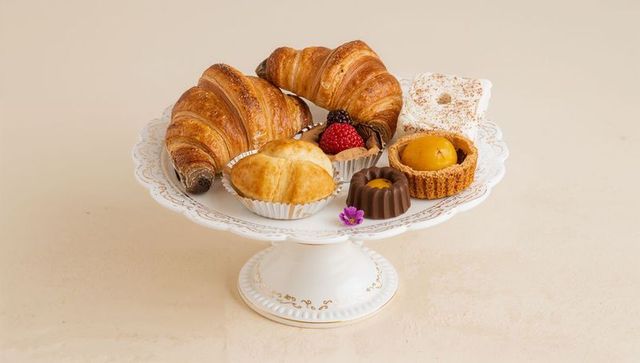 Elegant white gold-trim pedestal stand displaying assorted pastries and croissants