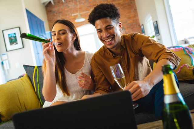Cheerful young biracial couple cheering while enjoying party on video call at home - Download Free Stock Photos Pikwizard.com