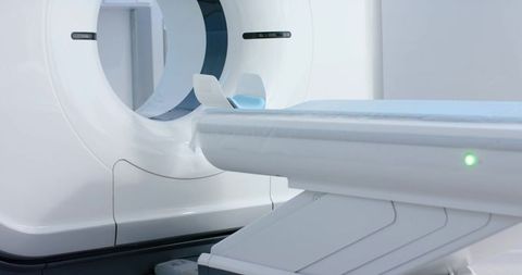 High-tech ct scanner gantry with motorized patient table and blue sheet in radiology room