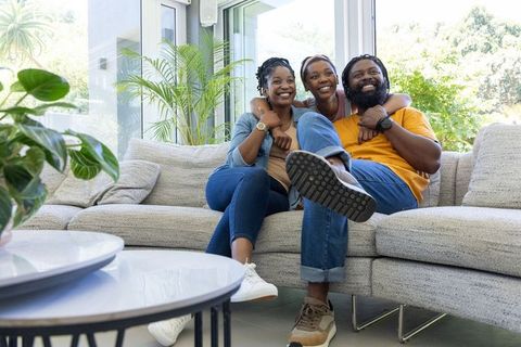 African american family relaxing on sofa with daughter hugging parents in living room