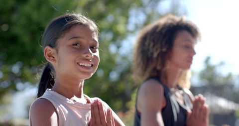 Mother and Daughter Practicing Yoga Meditation in Sunny Park Setting