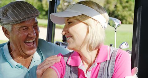 Happy senior golfers enjoying golf cart ride on fairway