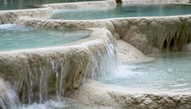 Turquoise terraced travertine hot springs cascading over mineral rims, calm thermal pools