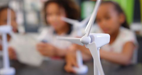 Children engaged in wind energy education with mini windmill