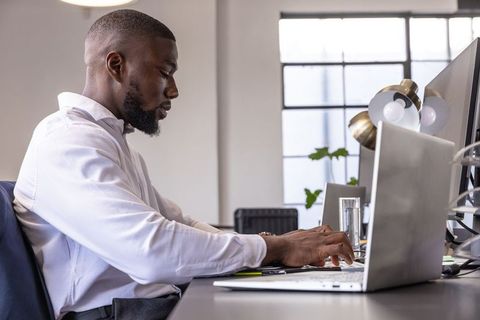 Focused Technologist Typing on Laptop in Modern Office