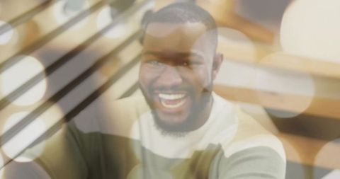 Laughing man wearing cream and olive sweater with warm bokeh and wooden slats double exposure