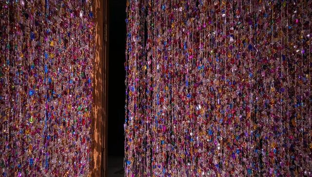 Crystal bead curtain catching colorful light in contemporary gallery corridor