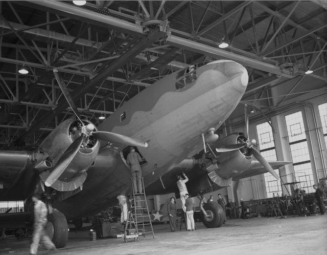 Ames mechanics working on C-46 airplane in front of hangar