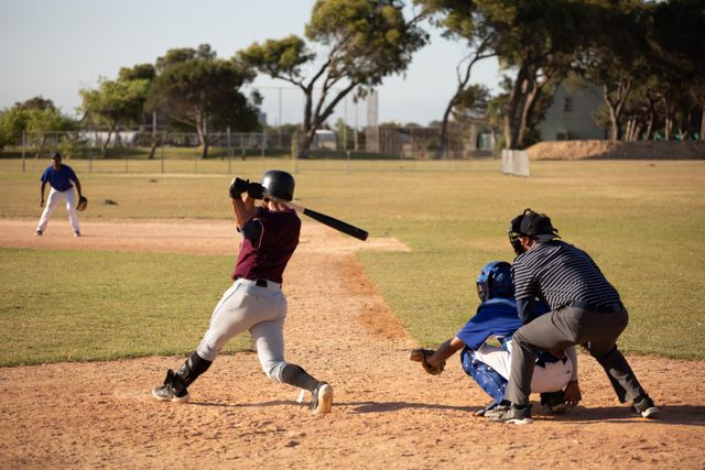 This image captures the intensity of a baseball game with players actively competing on a sunny day. Ideal for use in sports-related articles, advertisements for athletic gear, or promotional materials for baseball events and leagues.