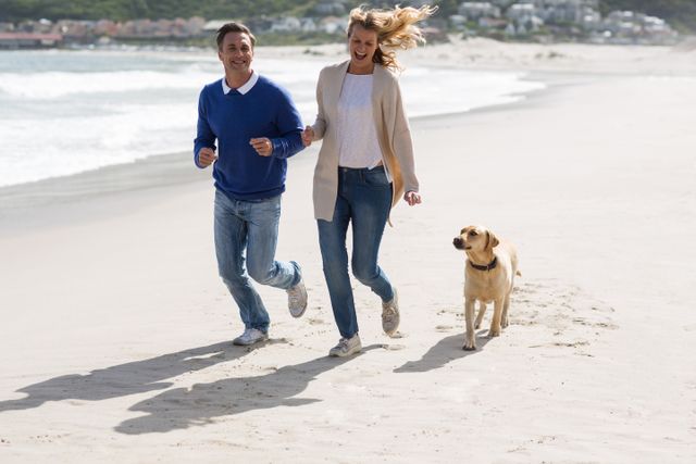 Romantic mature couple walking on the beach with their dog